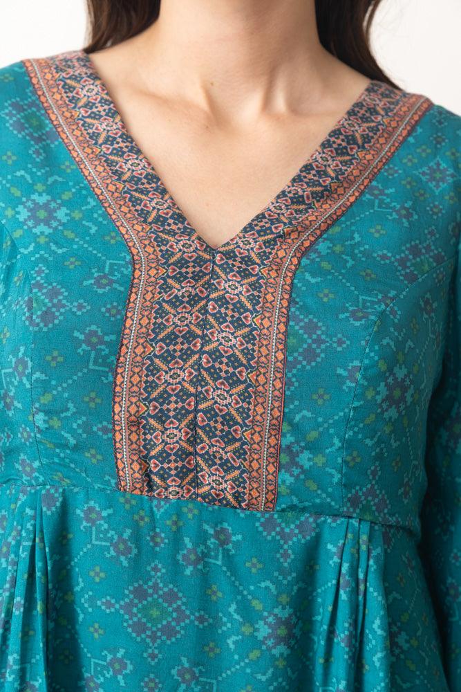 Aqua silk mini dress with all-over geometric Patola print, V-neck, and intricate contrasting trim.