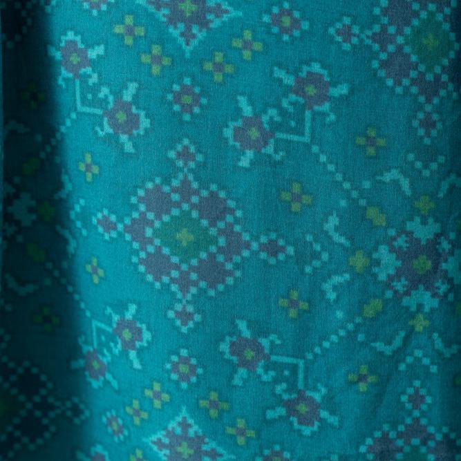 Close-up of Livia Aqua Short Dress silk fabric with all-over Patola geometric print in teal, green, and purple.