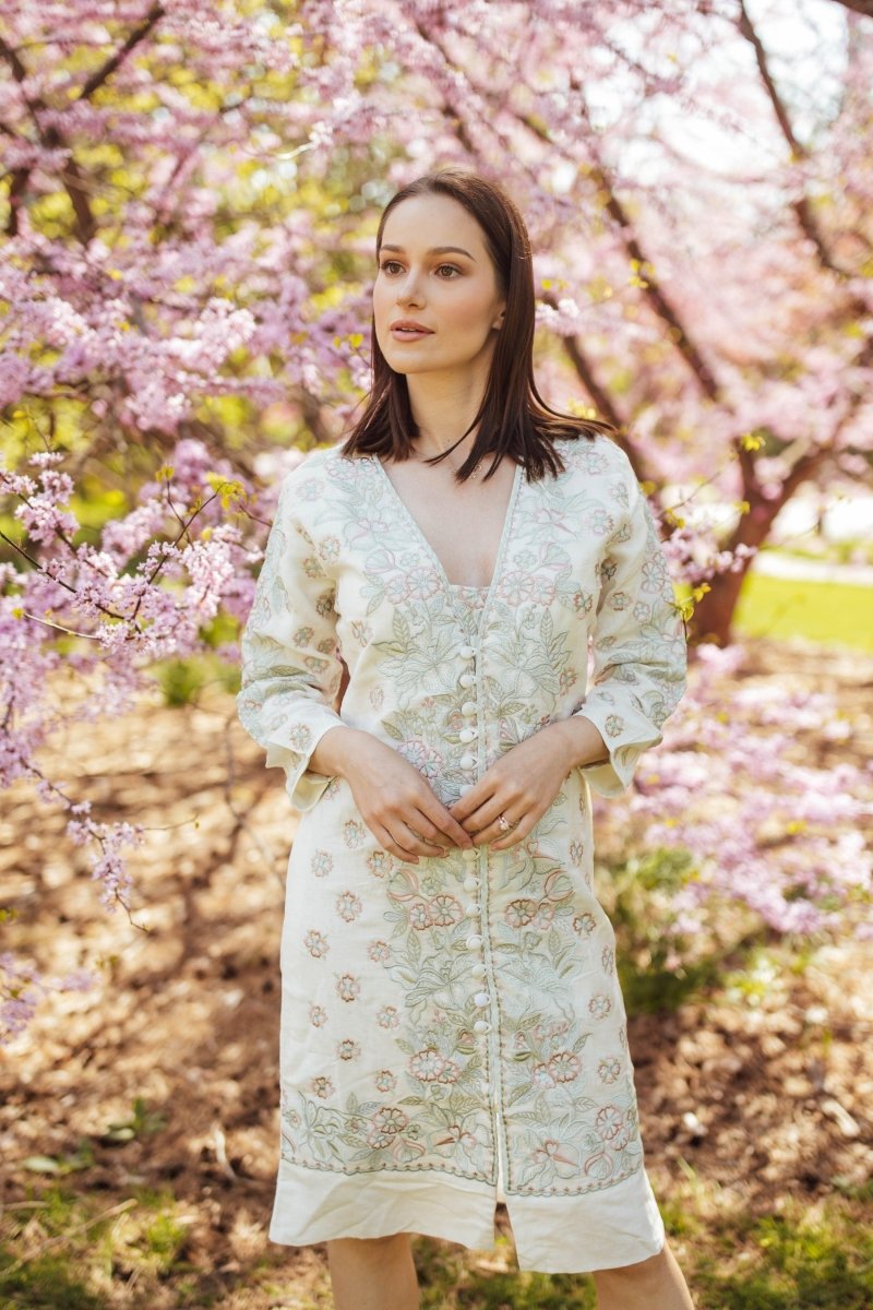 Off-white linen midi dress with front buttons, 3/4 sleeves, and all-over floral hand embroidery.