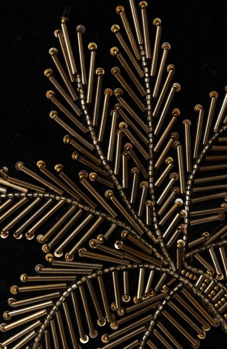 Close-up of golden Varli hand embroidery with cut-dana beads on luxurious black velvet fabric.