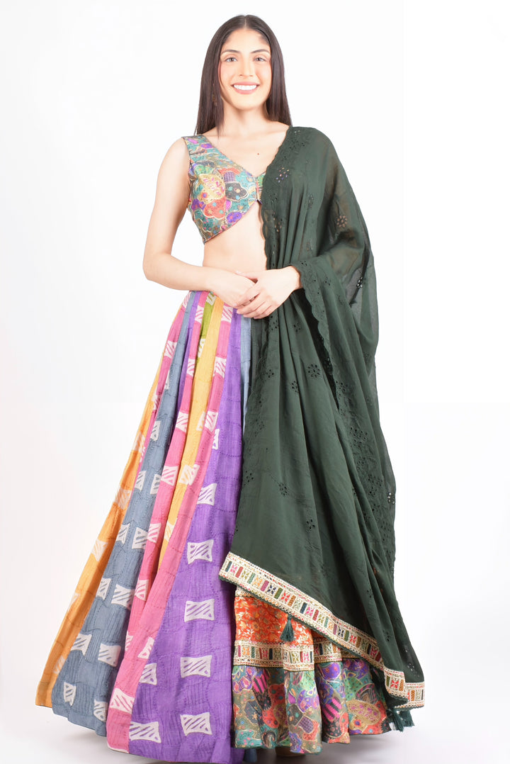 Smiling woman in a vibrant Mul Cotton Chaniya Choli with a multi-color flare skirt, embroidered blouse, and dark green dupatta.