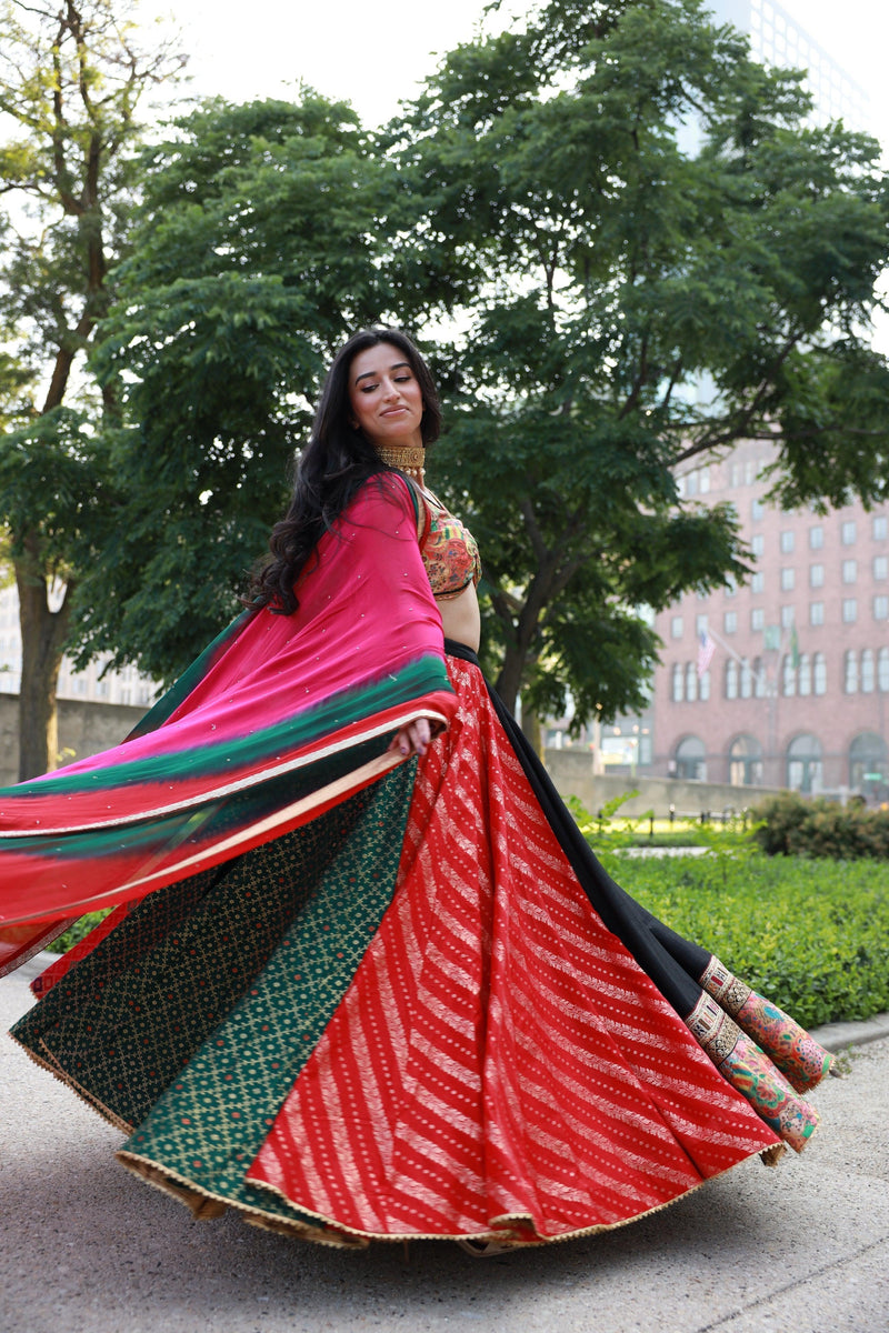 Multi-color full flare Chaniya Choli set with a black lehenga, red, green, pink panels, and a tie-dyed dupatta, perfect for Garba.