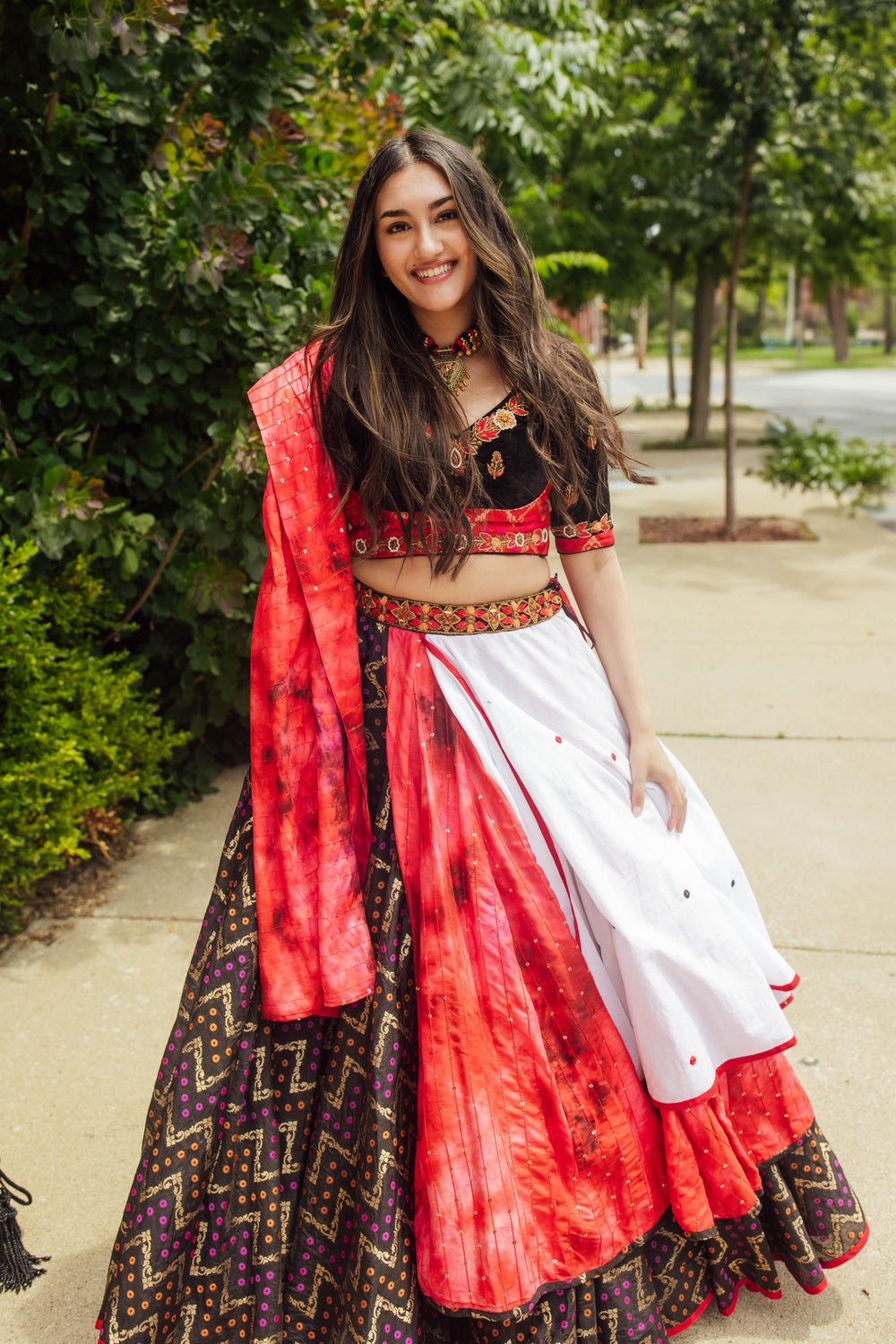 Multi-color layered chaniya choli with red, white, black, mirror work, and sequin details, perfect for dramatic twirls.