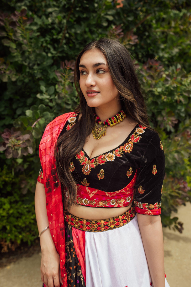 Multi-color layered Chaniya Choli: black velvet blouse, red dupatta, white and black skirt with embroidery.
