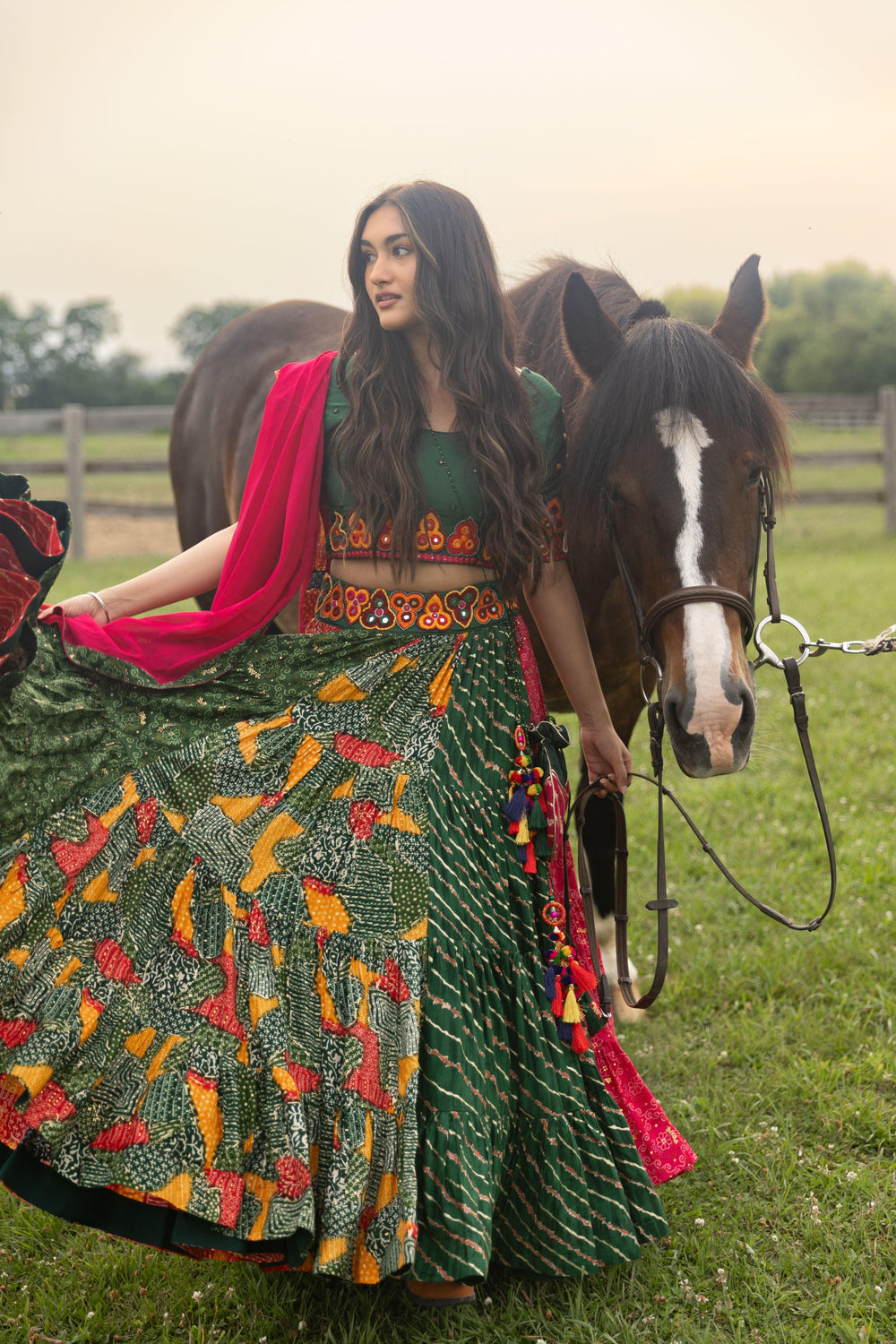 Multicolor full flare Chaniya Choli set with kachi embroidery, U-back blouse, and pink dupatta, next to a horse.