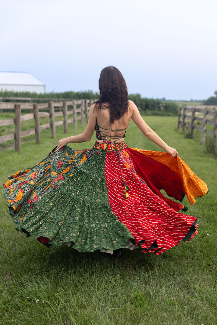 Woman in a dramatic multi-color full flare Chaniya Choli set, twirling outdoors.
