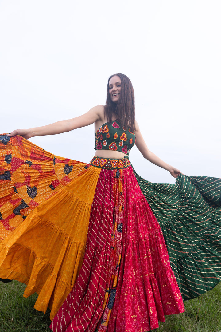 Woman in multi-color full flare Chaniya Choli set, twirling dramatically. Halter neck blouse, tiered skirt.