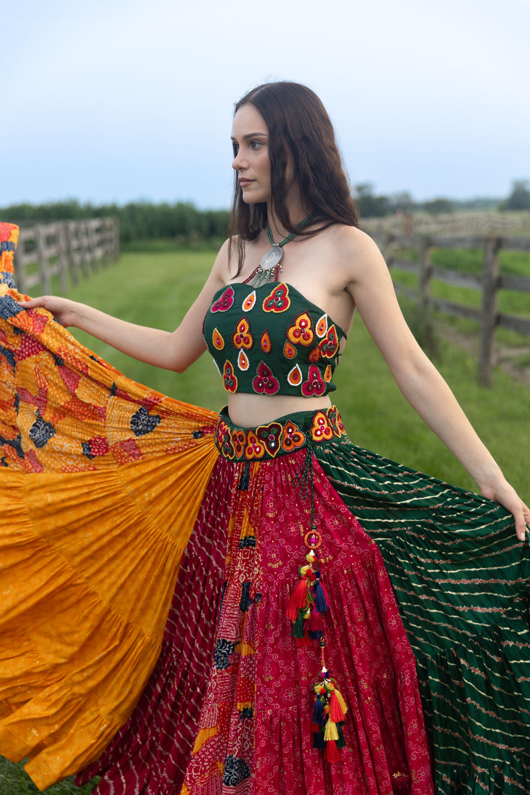 Woman in a multi-color cotton-silk Chaniya Choli set with a dramatic flare, halter-neck blouse, and kachi embroidery.