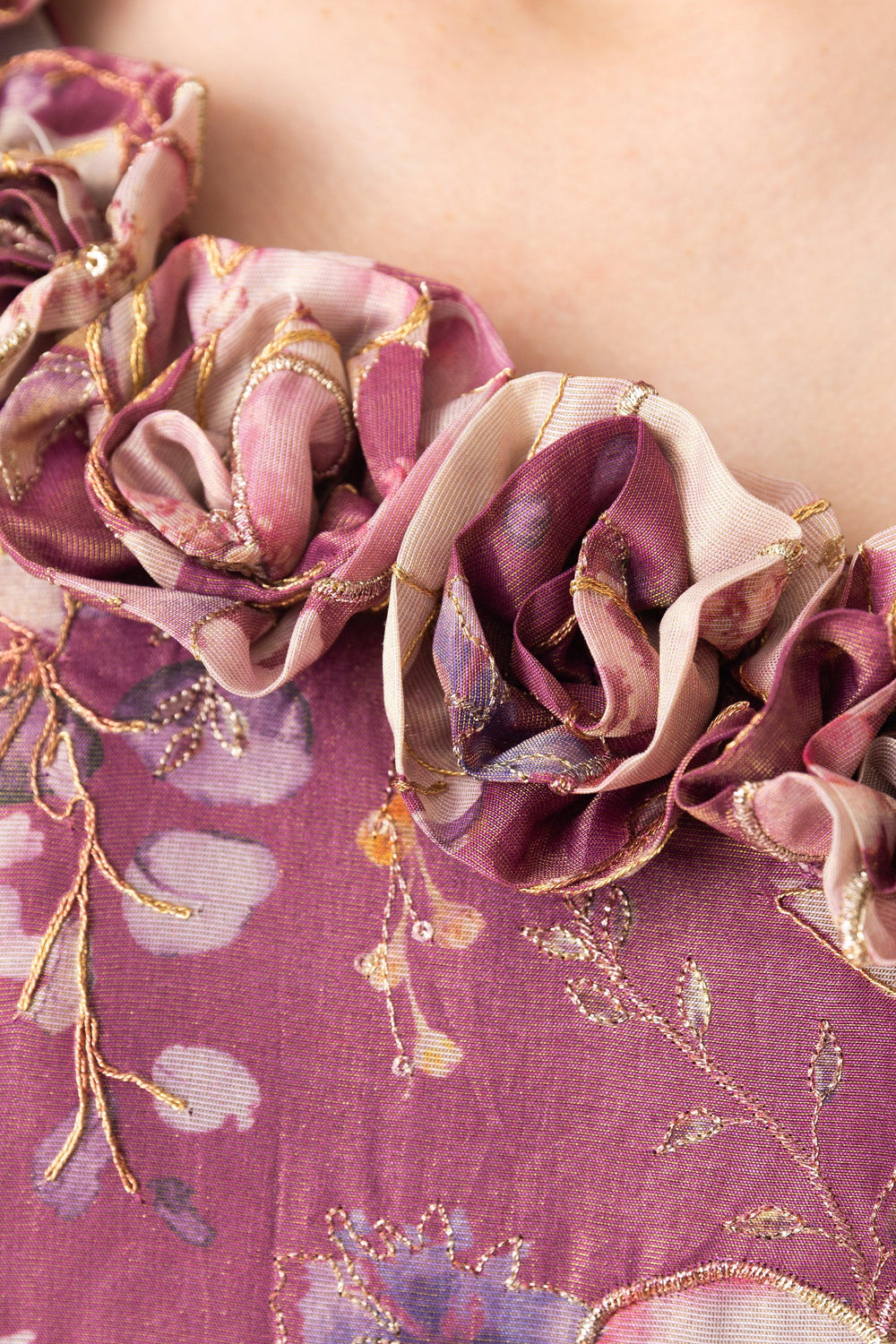 Close-up of a pink floral organza one-shoulder gown with 3D fabric flowers and gold embroidery.