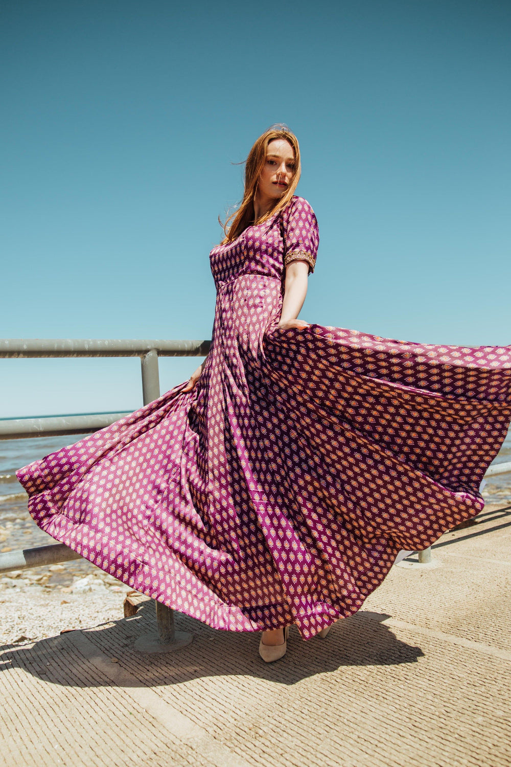 Purple silk A-line gown with gold embroidery, half sleeves, and flowing skirt, worn outdoors.