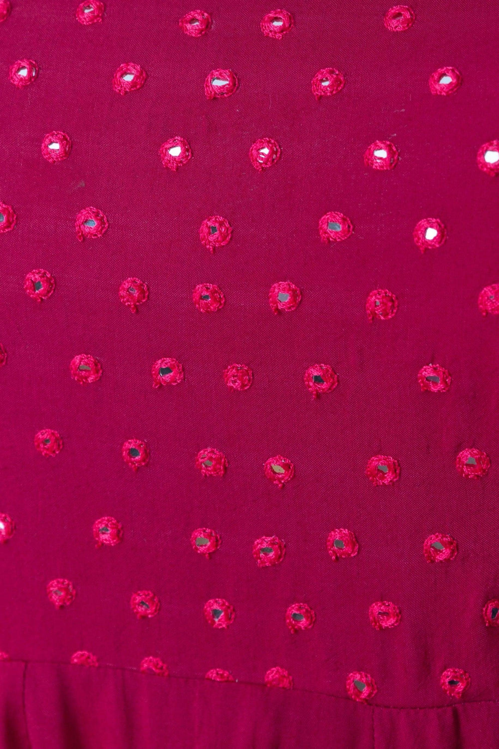 Close-up of a red silk gown with intricate mirror embroidery, showcasing the detailed fabric texture.