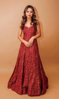 Woman in a red cotton-silk off-shoulder gown with intricate embroidery and an all-over patterned design.