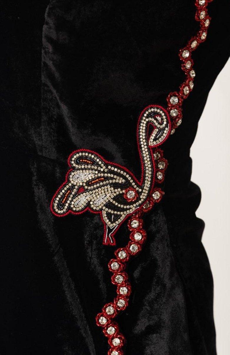 Close-up of Regina Black Velvet Mini Dress with hand-embroidered flamingo and rhinestone border.