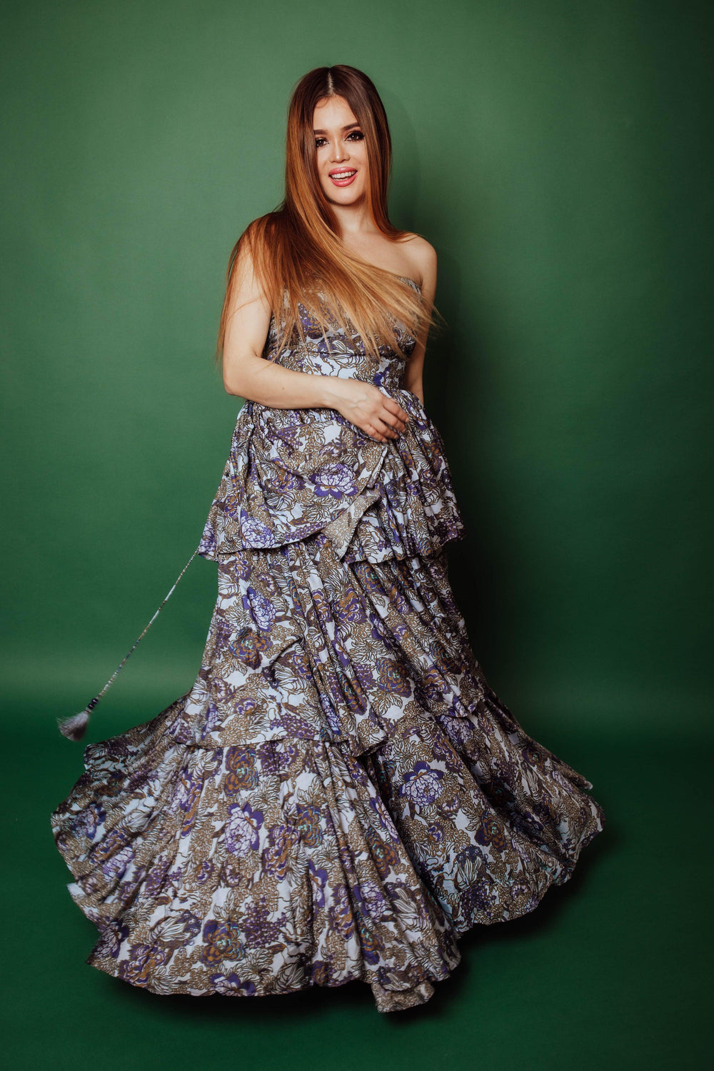 Silk tiered floral convertible long dress with micro-pleating, worn strapless against a green background.