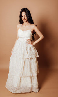 Model wearing a tiered off-white georgette long dress with a halter neck and flowy silhouette.