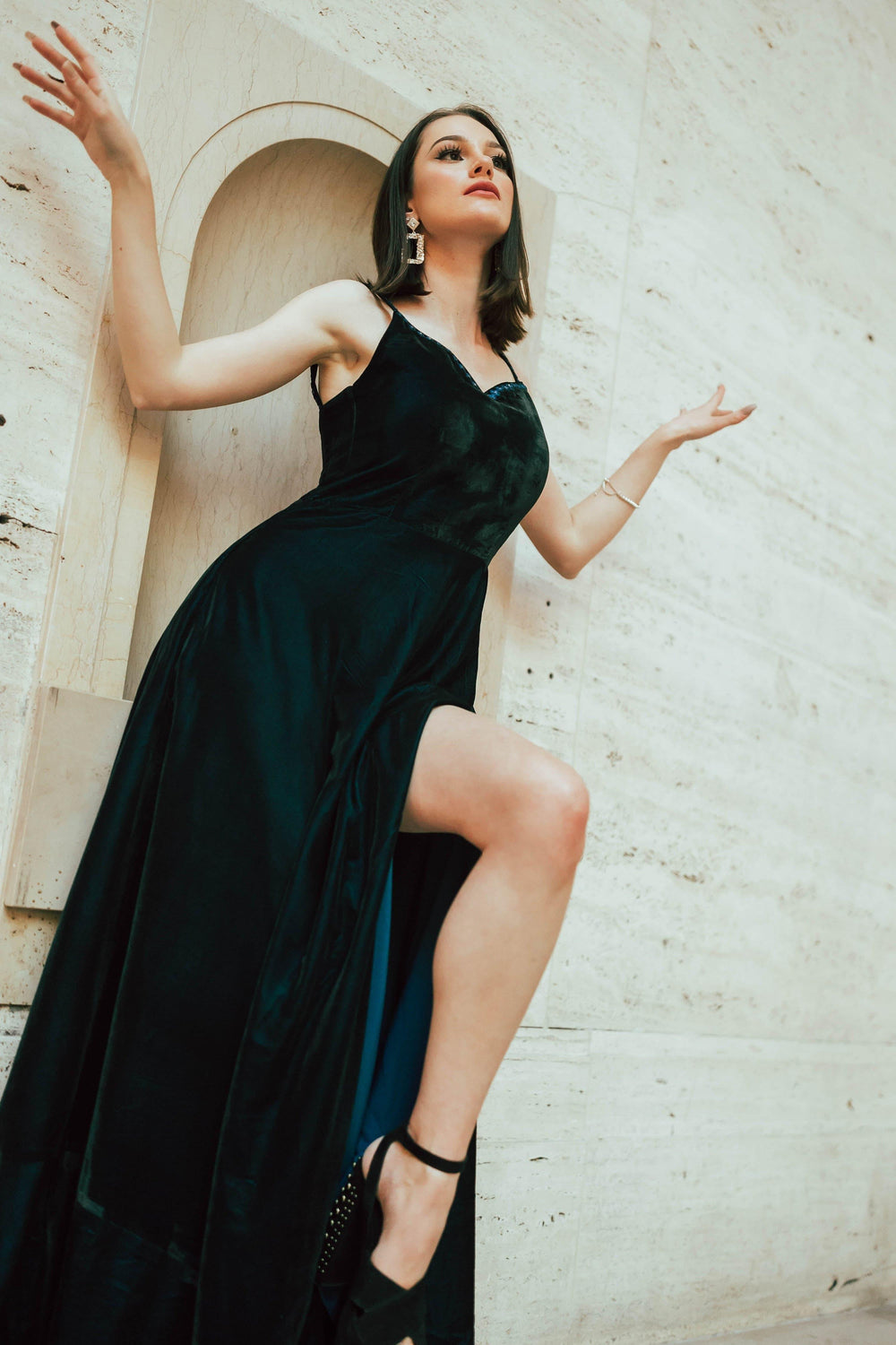 Teal blue velvet gown with front slit, mirror work neckline, and sleeveless design.