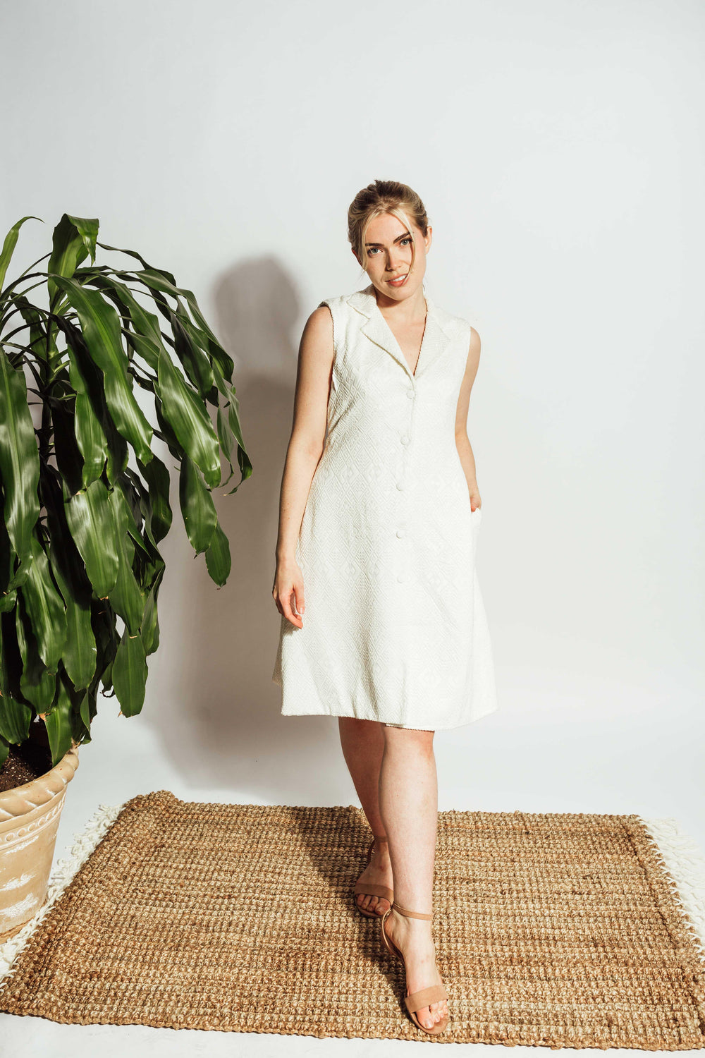 White sleeveless blazer dress with self-thread geometric embroidery, notched lapel, and front buttons.
