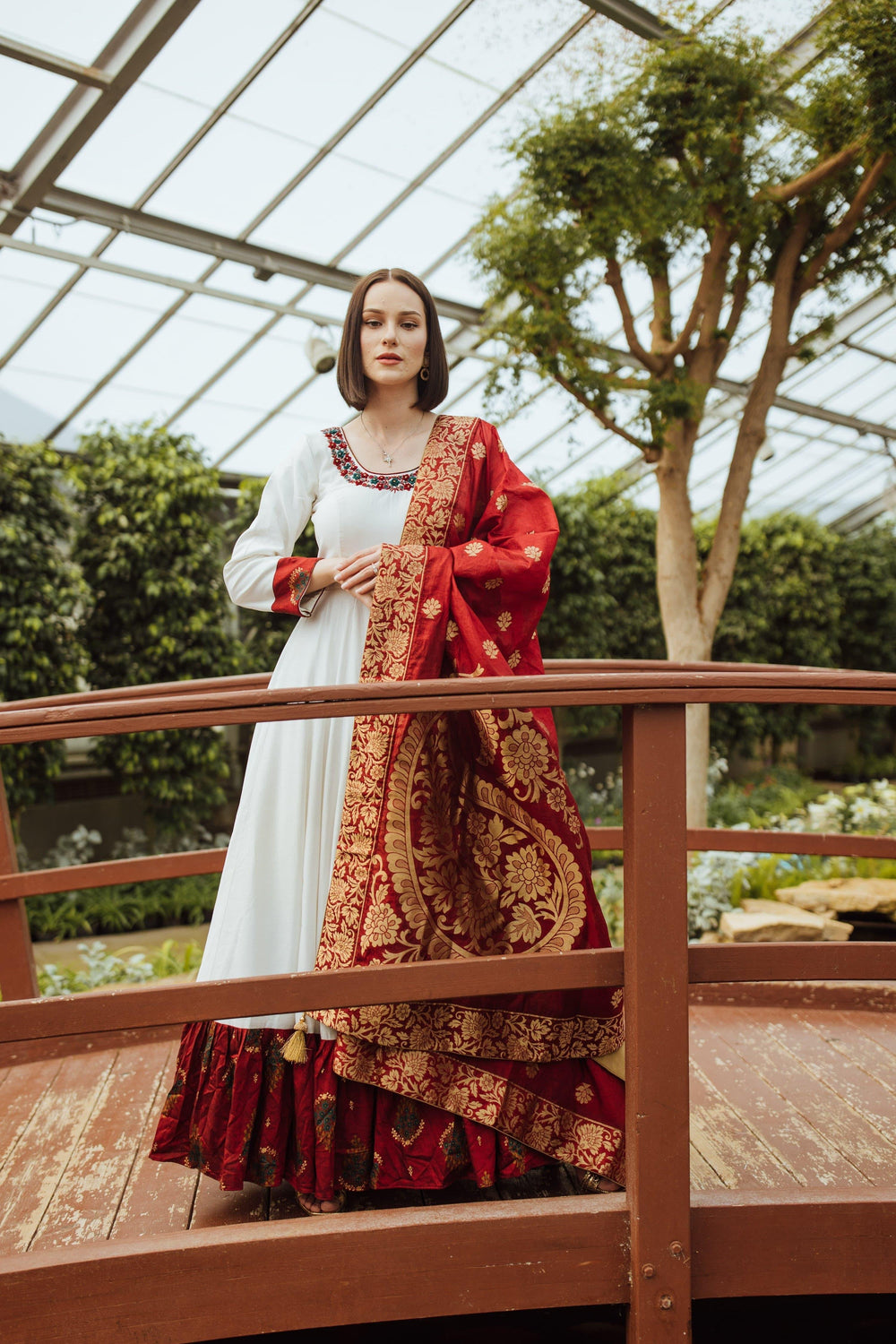 White silk long dress with red resham and gold embroidery, paired with a crimson Banarasi silk drape.