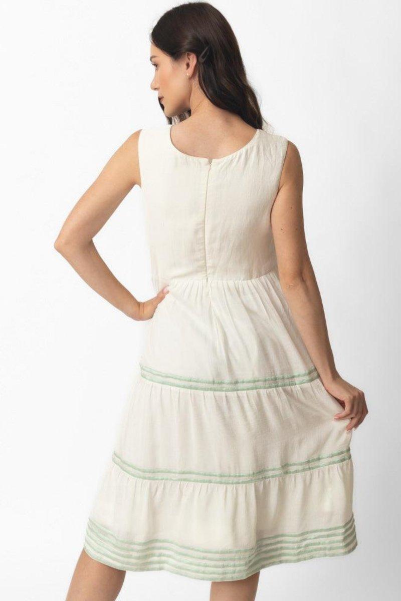 White midi dress with sleeveless design, tiered skirt, and subtle green hand-embroidered patterns.