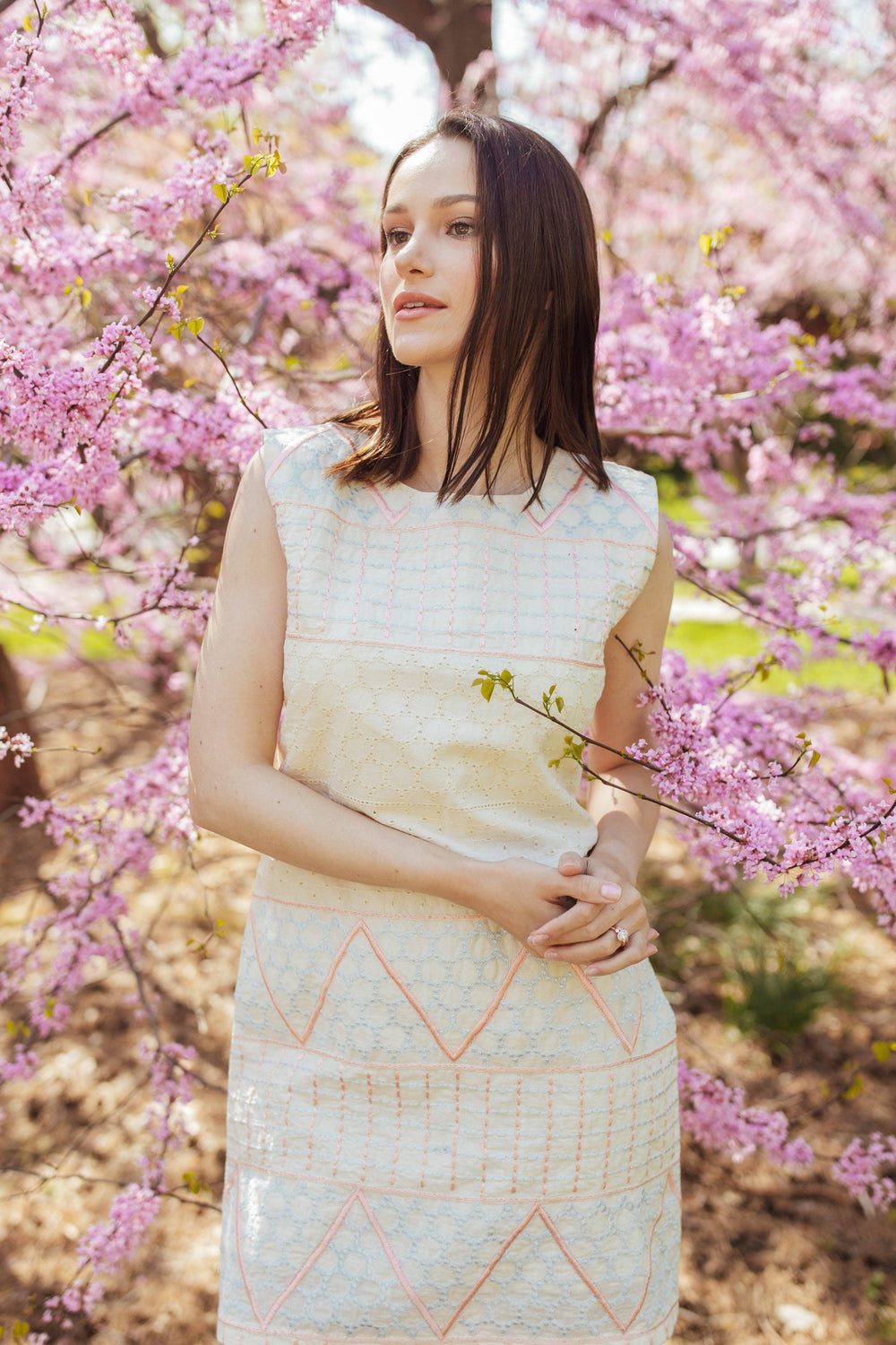 White cotton mini dress with geometric coral and ivory eyelet embroidery, sleeveless.