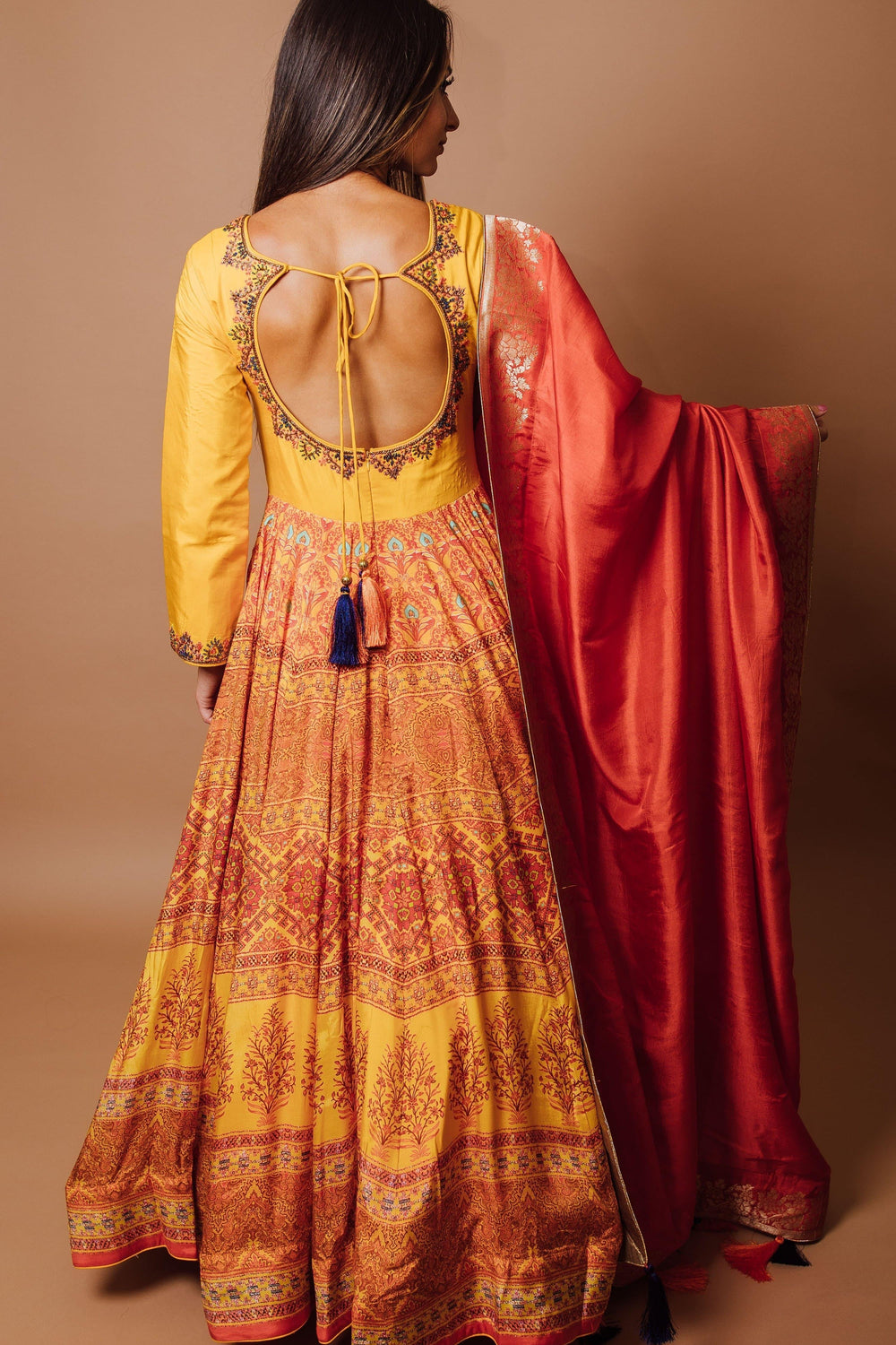 Yellow silk A-line gown with open back, long sleeves, traditional print skirt, and red georgette drape.