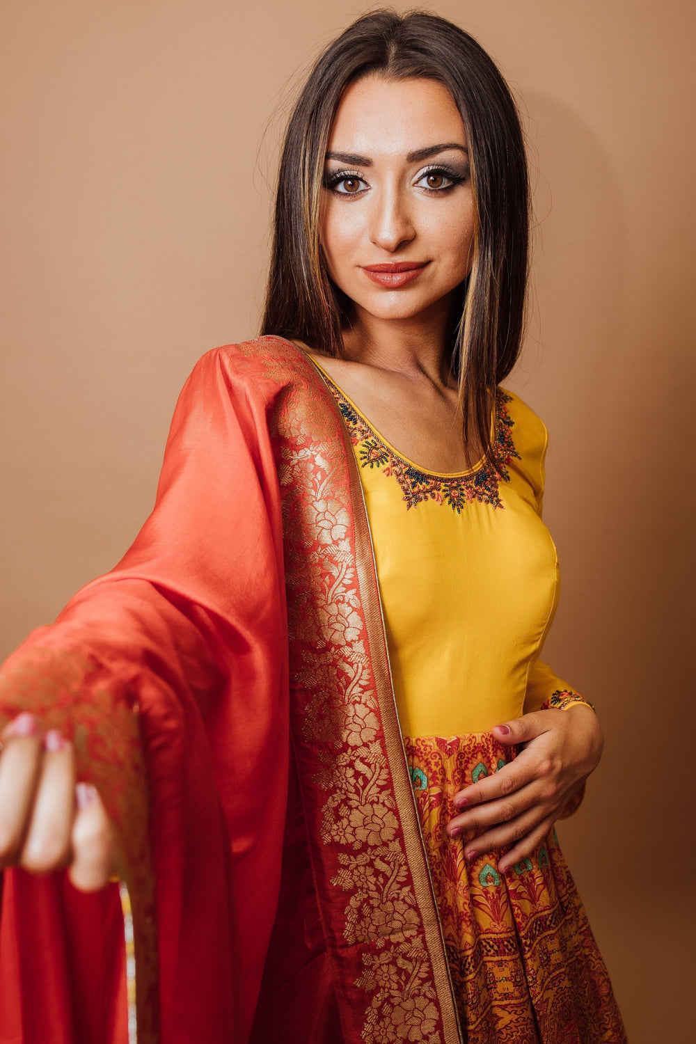 Woman in a yellow silk A-line gown with an embroidered neckline, printed skirt, and red georgette drape.
