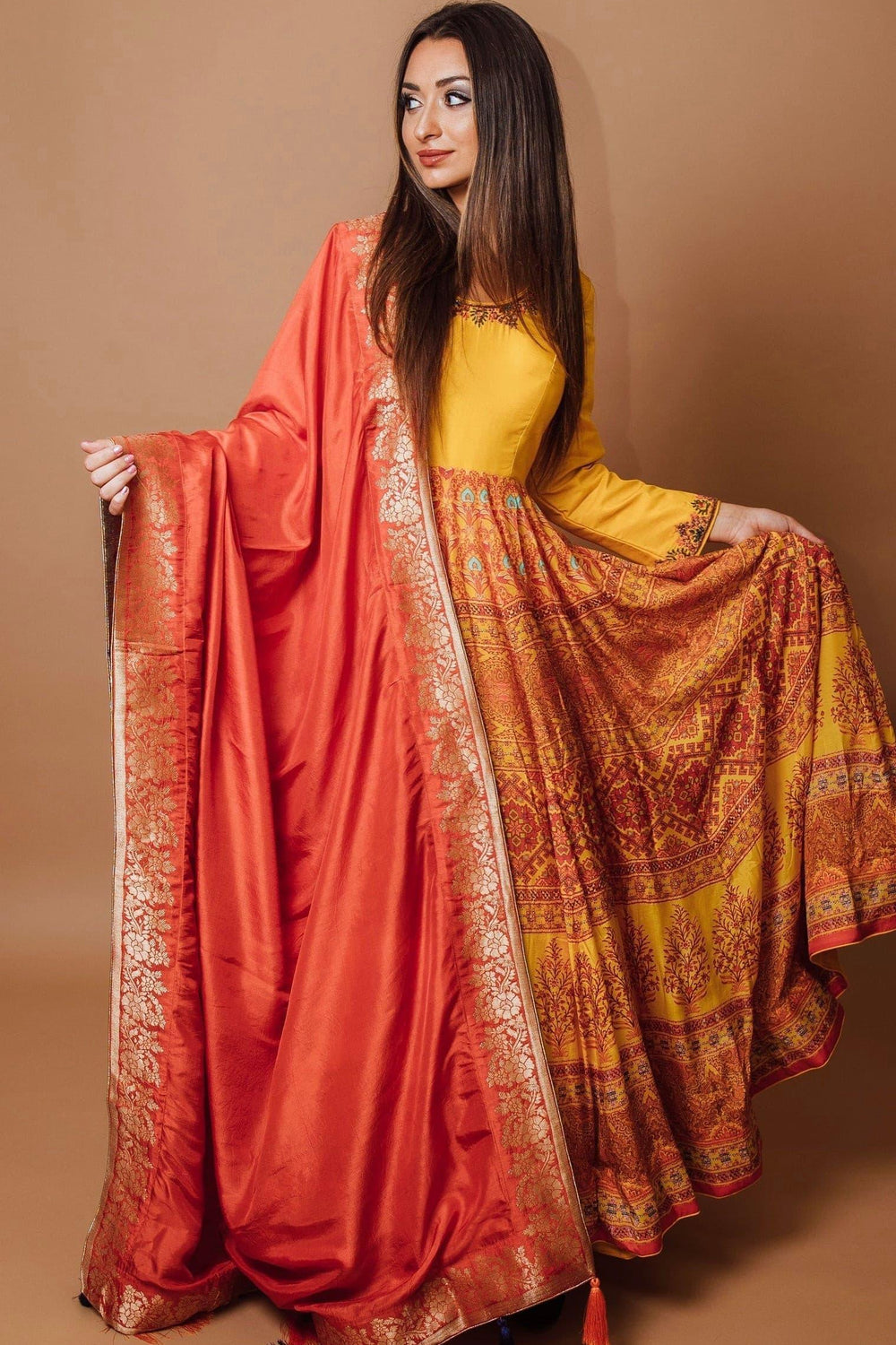 Yellow silk A-line gown with embellished neckline, traditional print skirt, and matching orange georgette drape.
