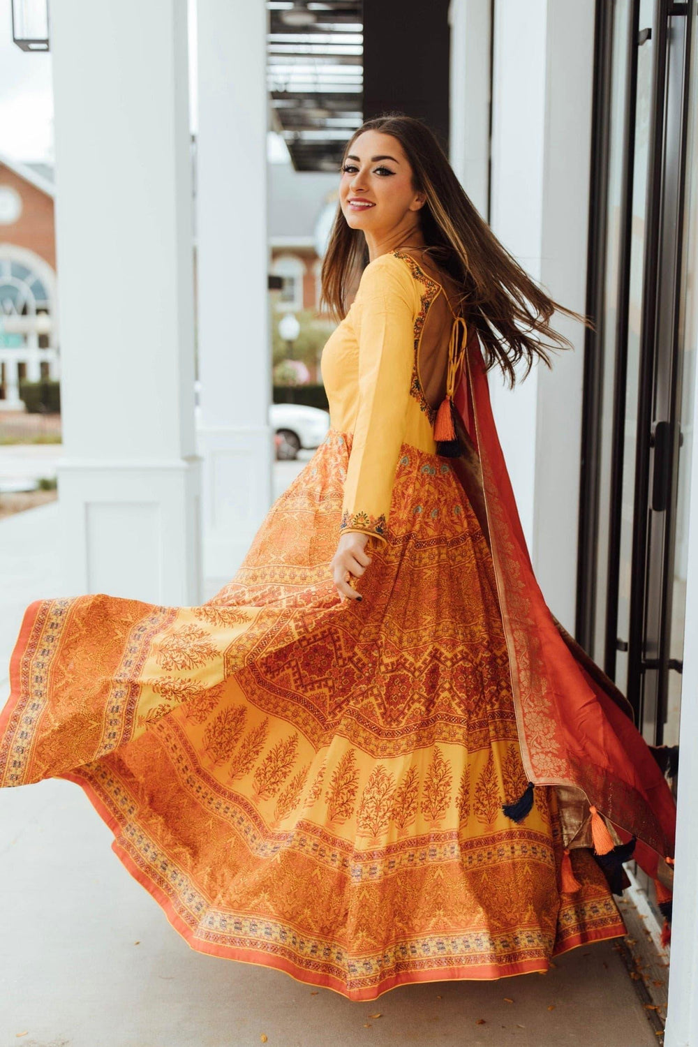 Yellow silk A-line gown with long sleeves, embellished neckline, and traditional print skirt.