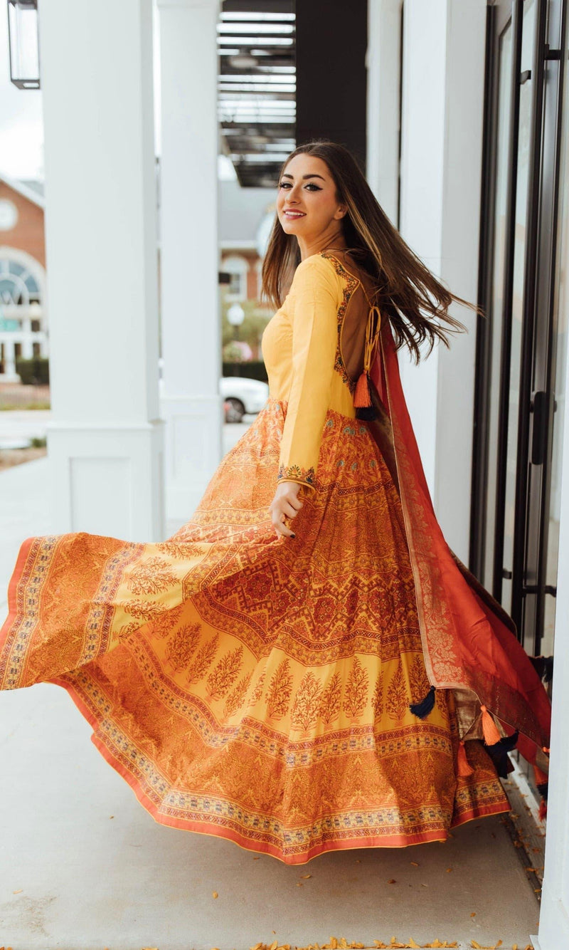 Yellow silk A-line gown with long sleeves, embellished neckline, and traditional print skirt.