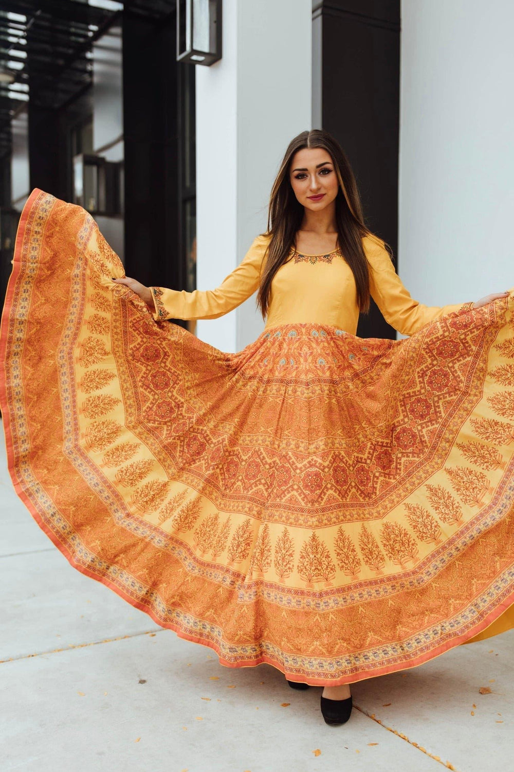Yellow silk A-line gown with solid mustard bodice, embellished neckline, and printed amber skirt.
