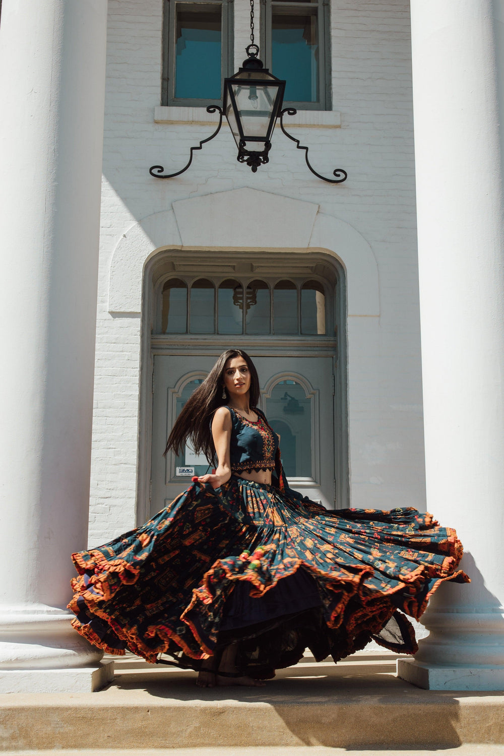 Woman in a blue full flare Chaniya Choli with vibrant ethnic prints, dramatic twirl, and Garba style.