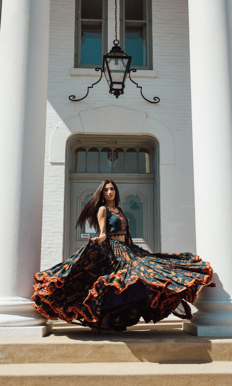Woman in a blue full flare Chaniya Choli with vibrant ethnic prints, dramatic twirl, and Garba style.