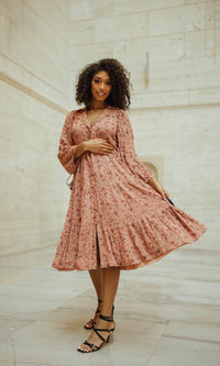 Pink tiered midi dress with long sleeves and floral print, worn by a model.