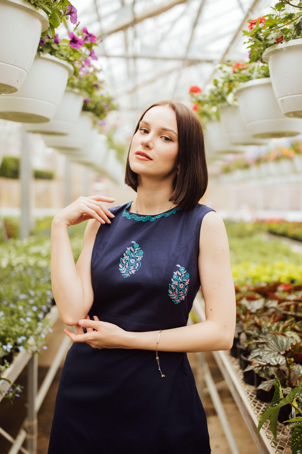 Navy cotton mini dress with blue hand block-printed patterns, sleeveless, modeled in a greenhouse.