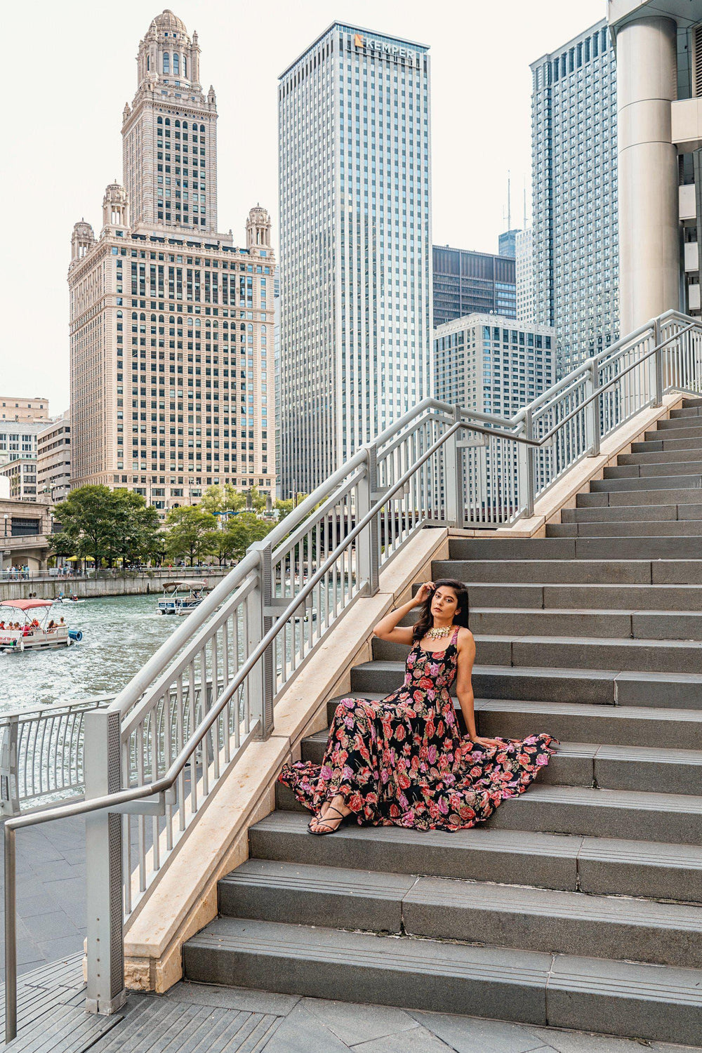 Woman in a magenta and purple ikat-inspired floral georgette long dress with a square neckline, sitting on stairs.