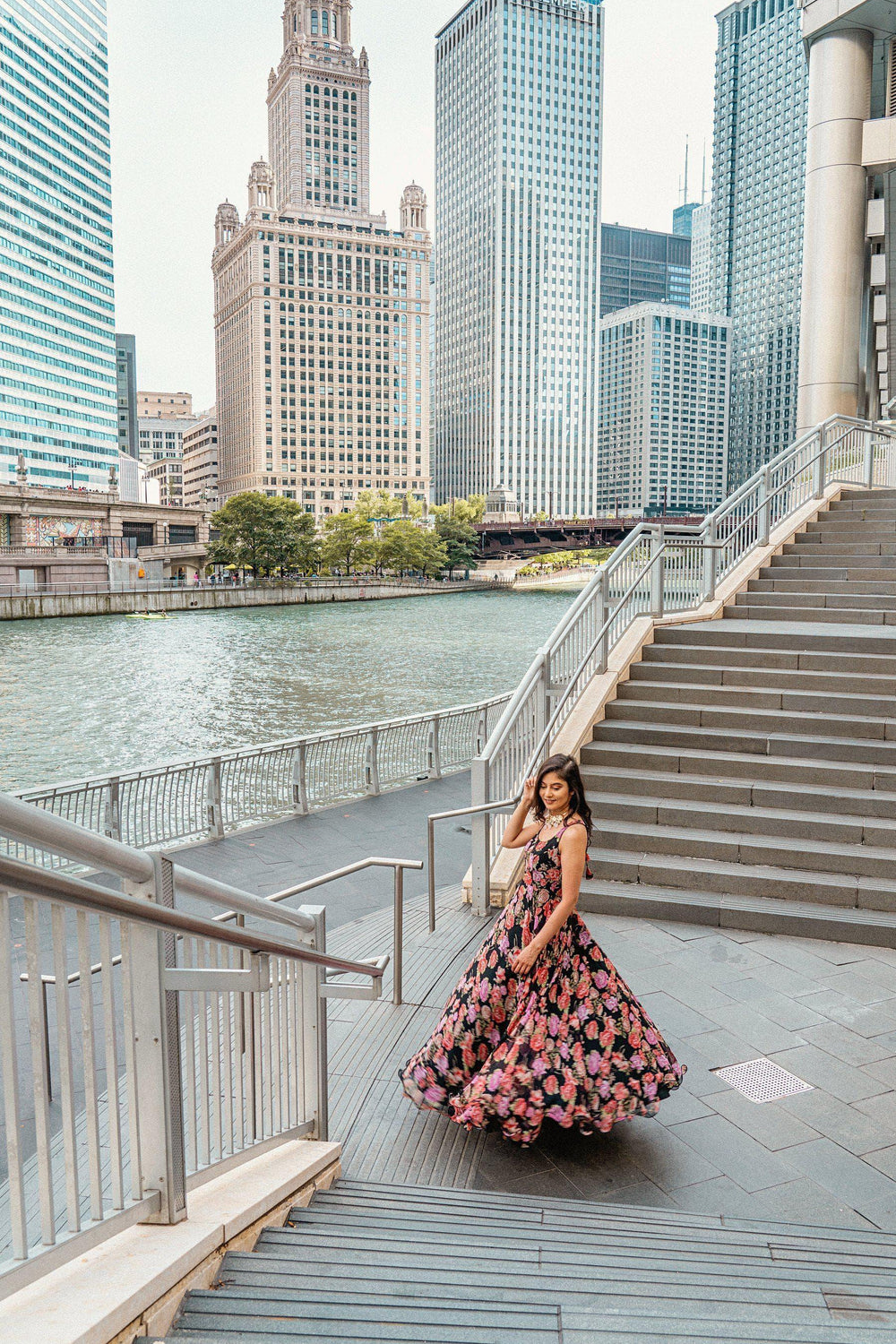 Woman in a magenta and purple ikat-inspired floral georgette long dress with a full silhouette, on city stairs.
