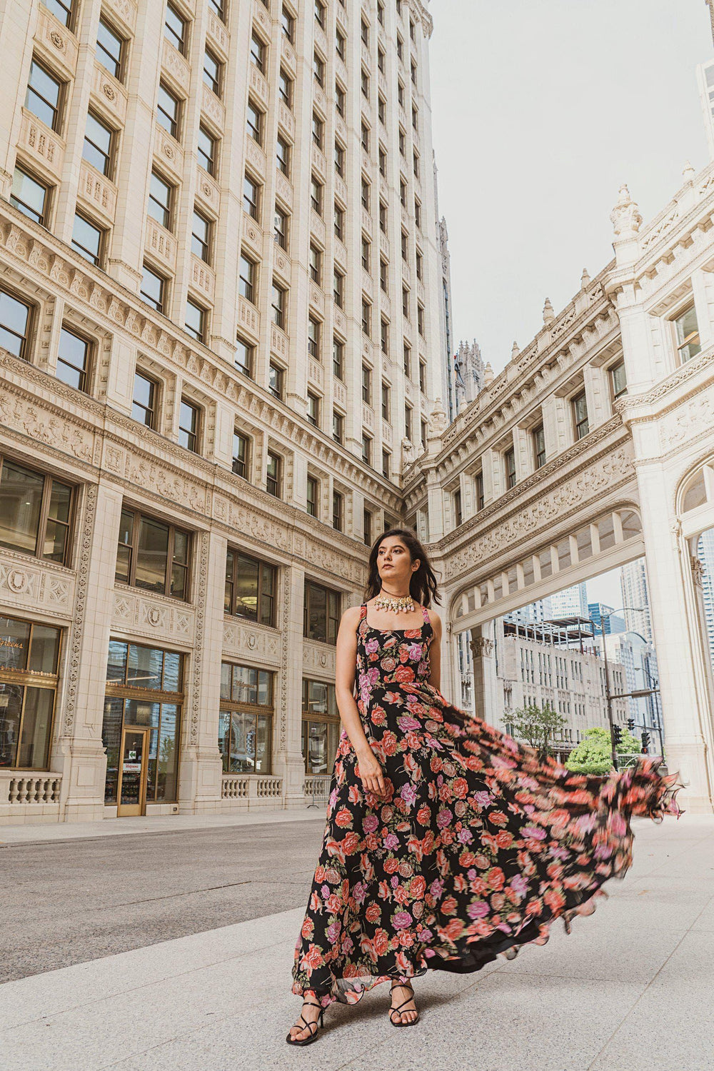 Woman in a flowing black georgette long dress with vibrant magenta and purple ikat-inspired floral print.