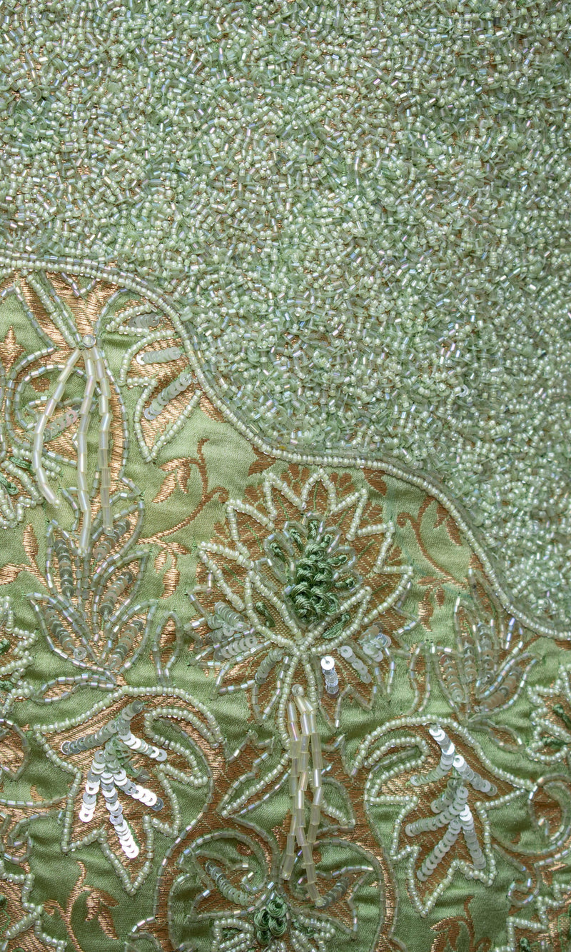 Close-up of green Banarasi silk dress with intricate gold embroidery, stonework, and bead detailing.