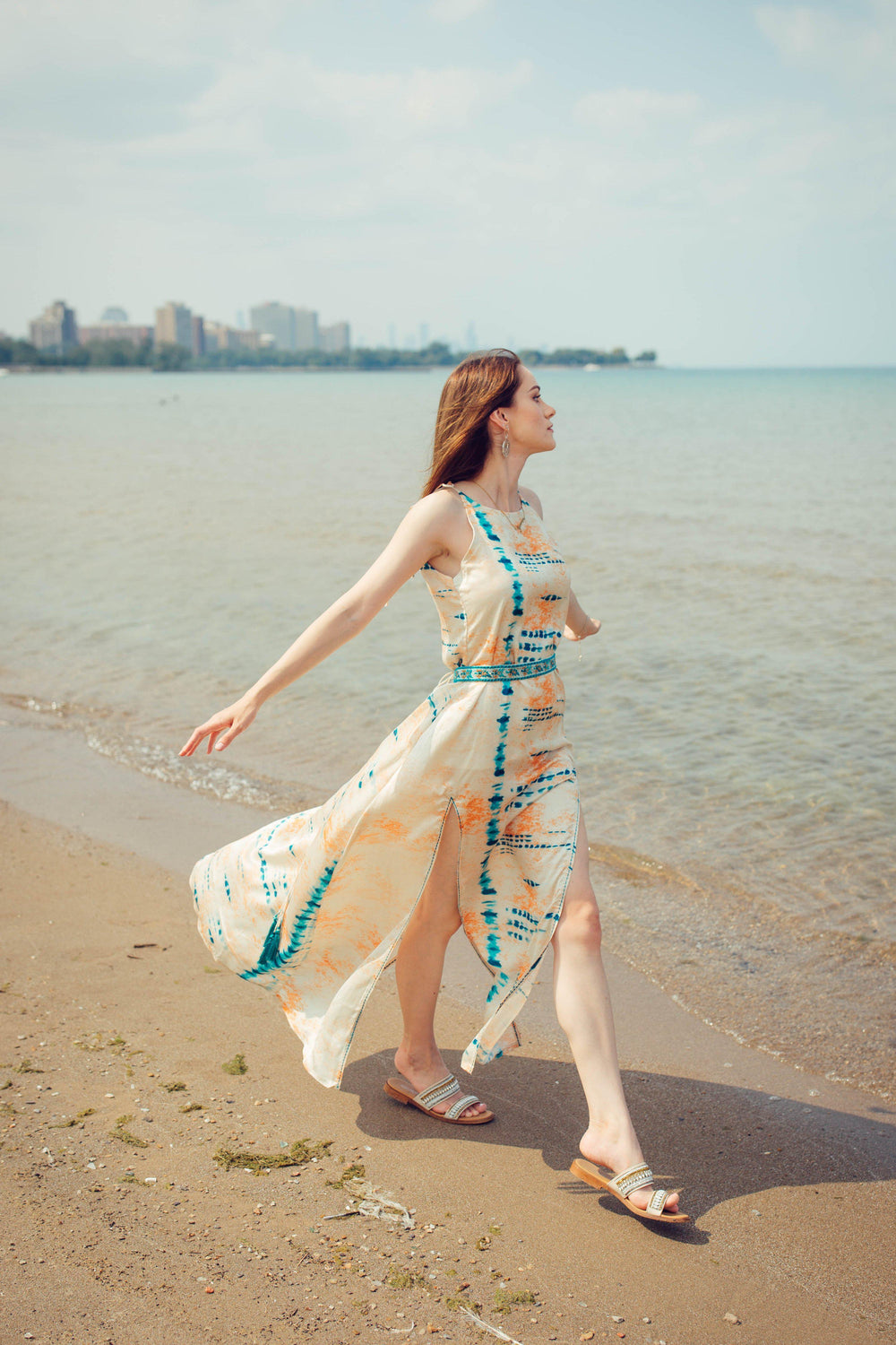 Off-white modal satin maxi dress with blue tie-dye, embroidered belt, and double slits on a beach.