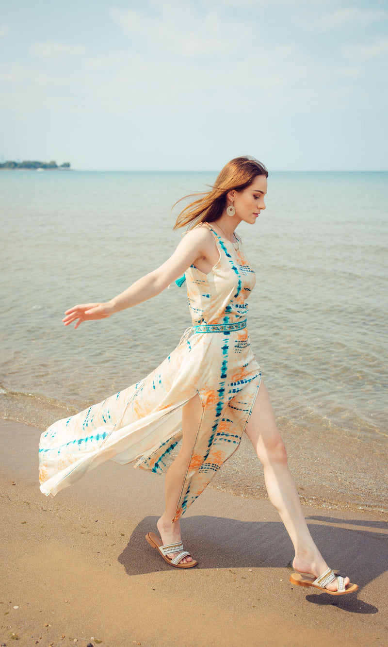Off-white modal satin maxi dress with blue tie-dye, embroidered belt, and double slits, worn on a beach.