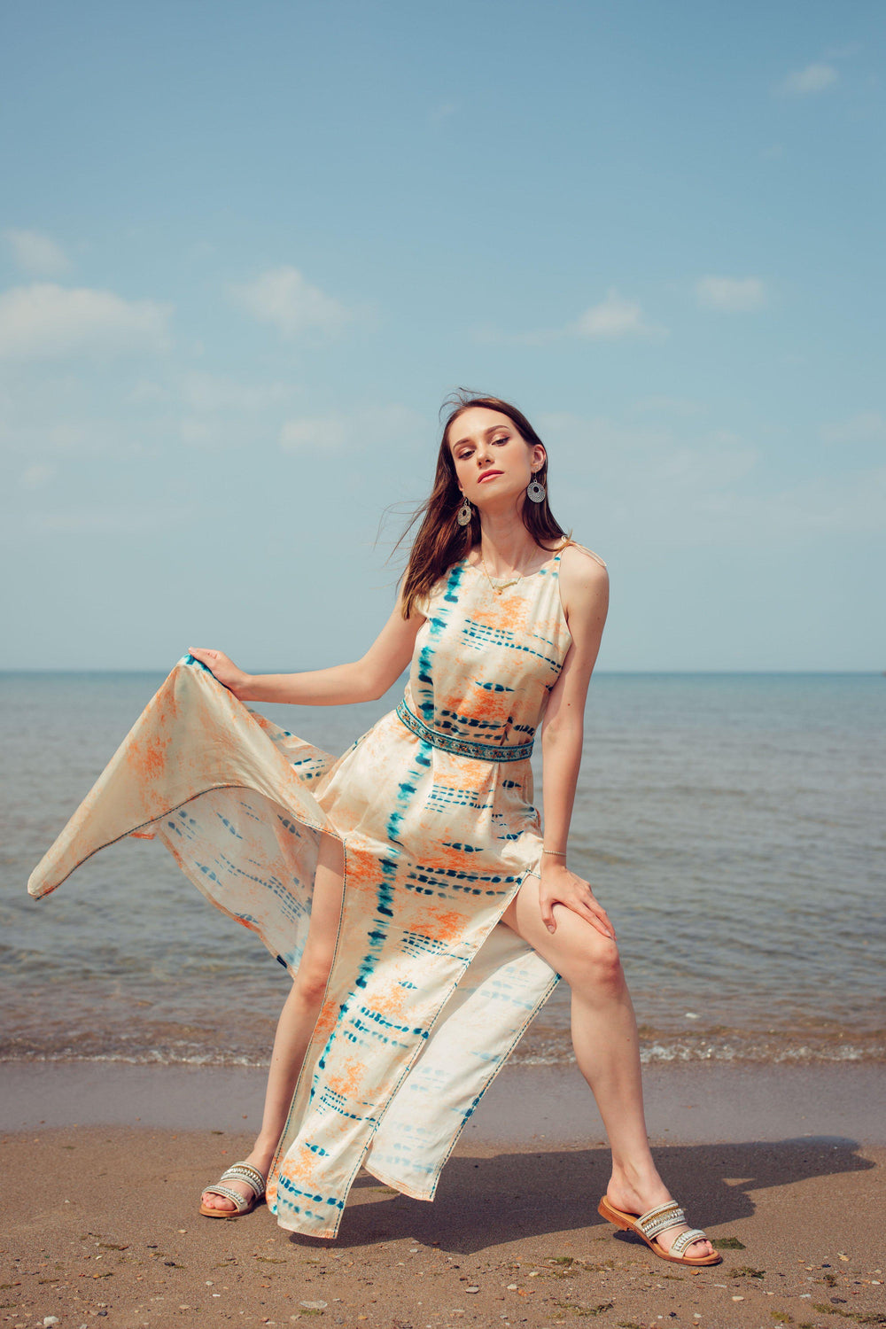 Off-white modal satin maxi dress with blue tie-dye, embroidered belt, and double slits on a beach.