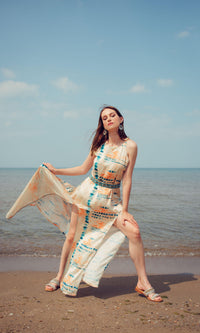 Off-white modal satin maxi dress with blue tie-dye, embroidered belt, and double slits on a beach.