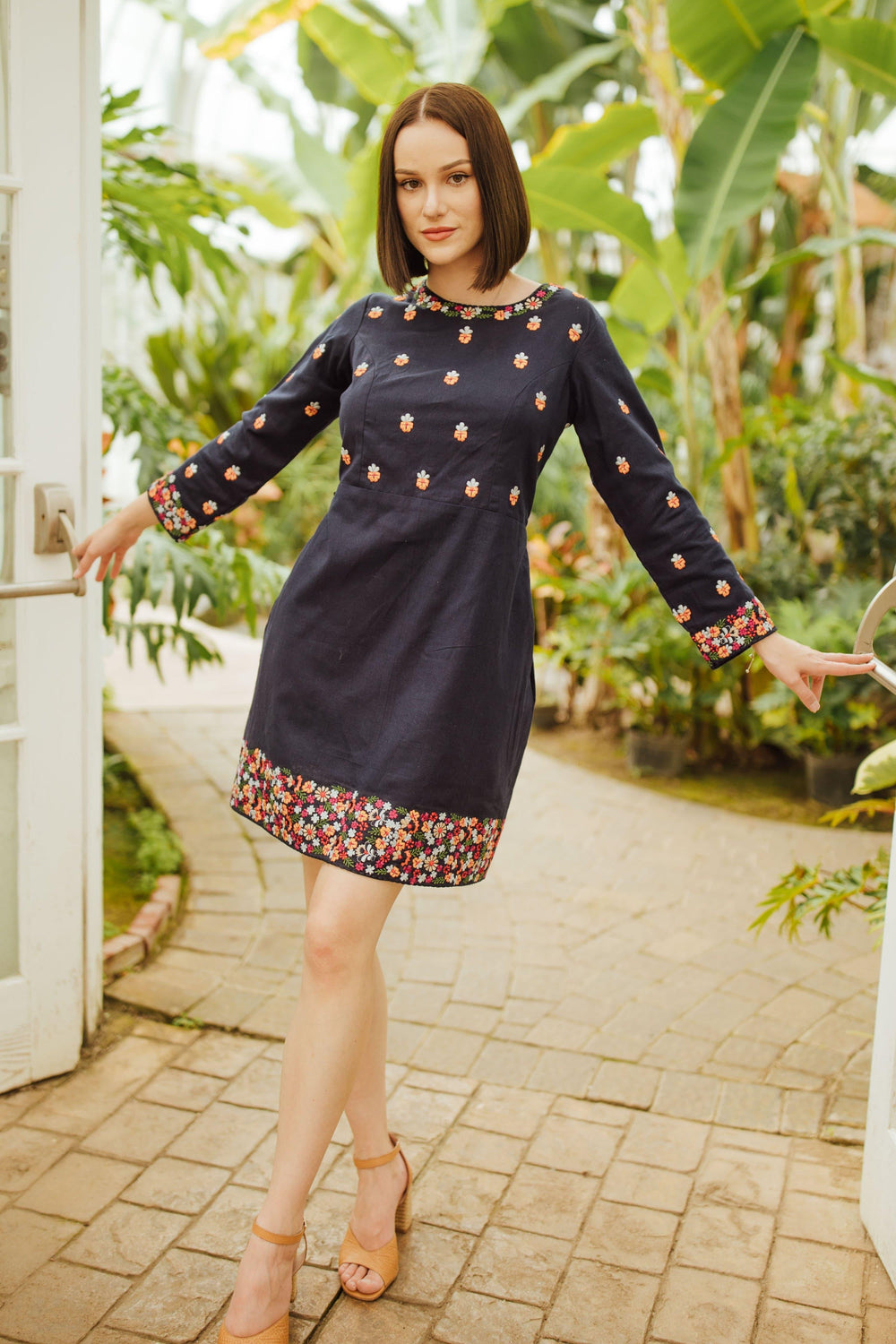 Navy cotton mini dress with long sleeves and colorful floral embroidery on the neckline, torso, and hem.