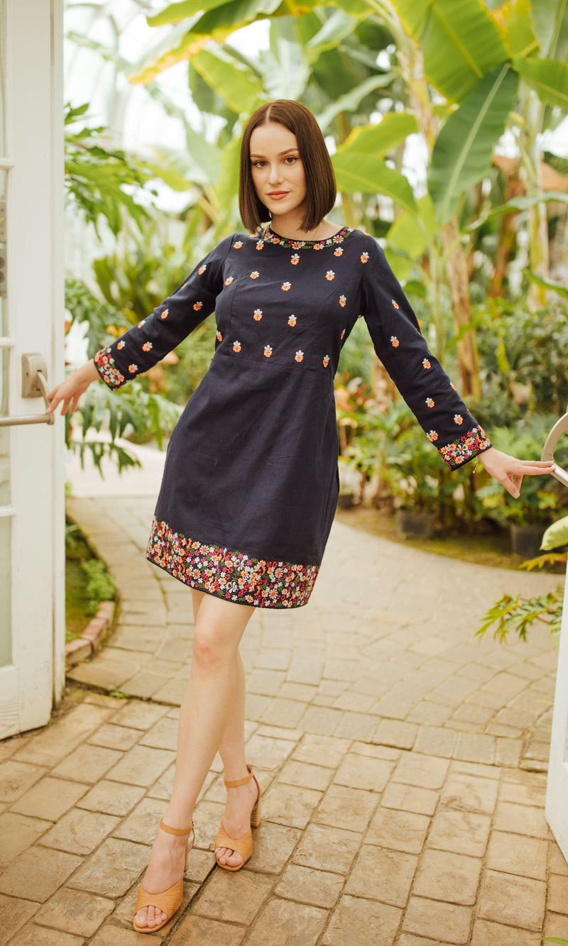 Navy cotton mini dress with long sleeves and colorful floral embroidery on the neckline, torso, and hem.