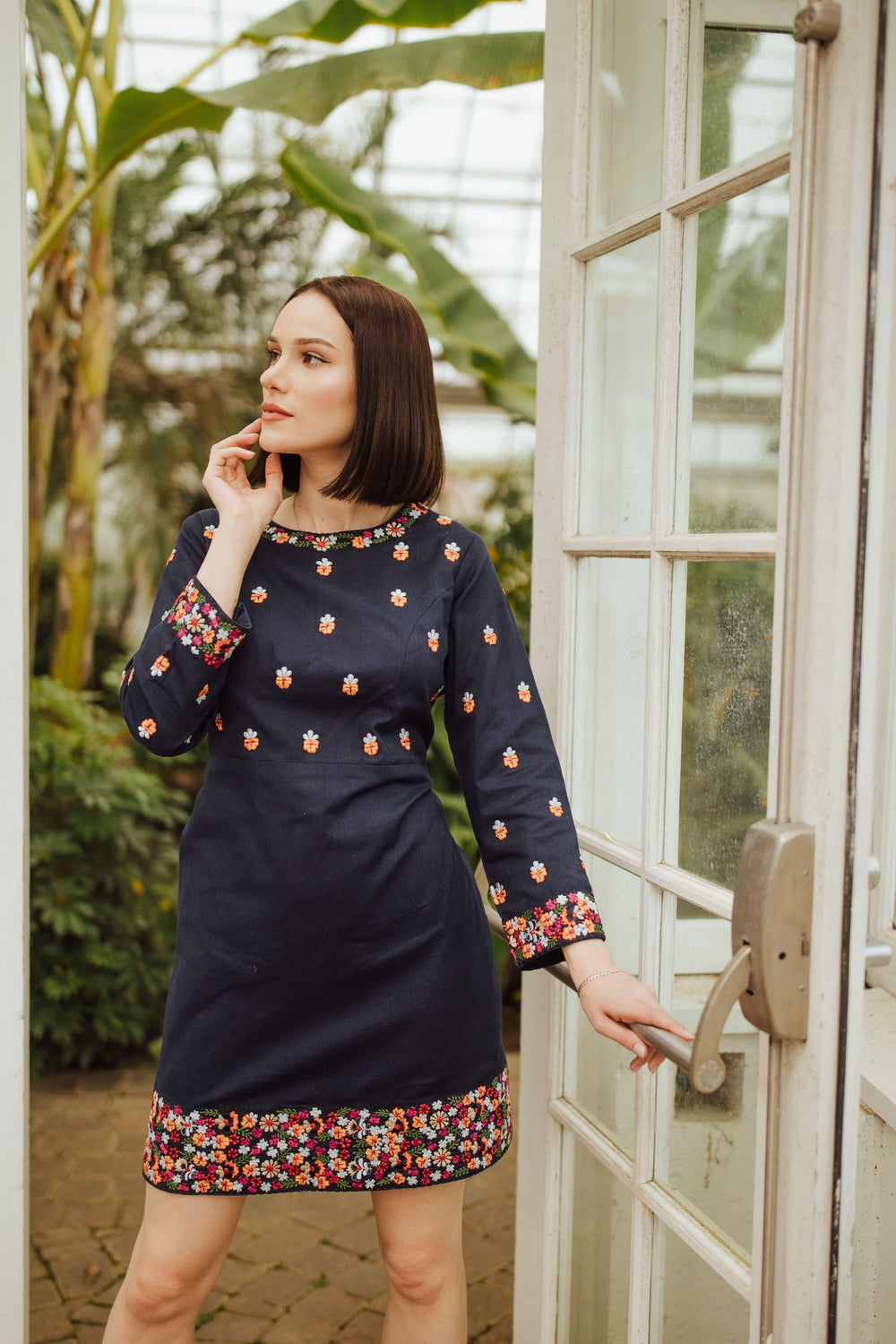 Navy cotton mini dress with colorful floral embroidery on neckline, sleeves, and hem.