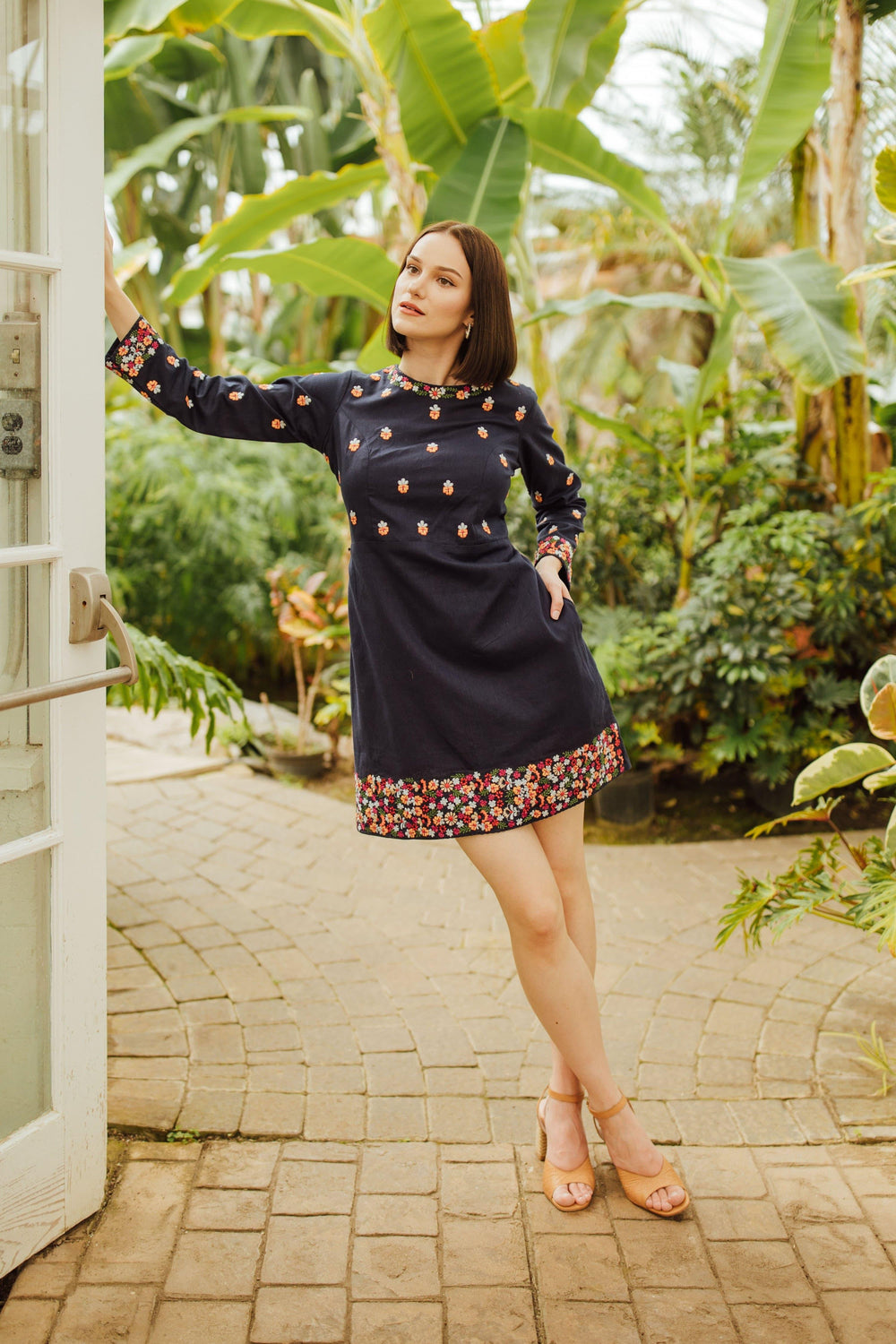 Navy cotton mini dress with colorful floral embroidery on long sleeves, neckline, and hem.