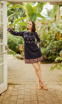 Navy cotton mini dress with colorful floral embroidery on long sleeves, neckline, and hem.