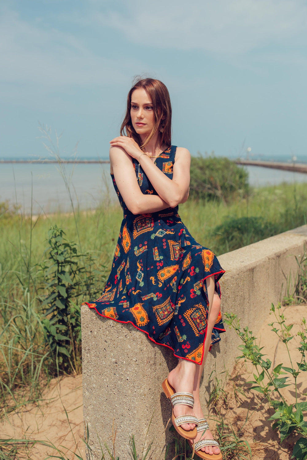 Navy rayon high-low dress with all-over patterns, V-neck, and sleeveless design, worn by a woman outdoors.