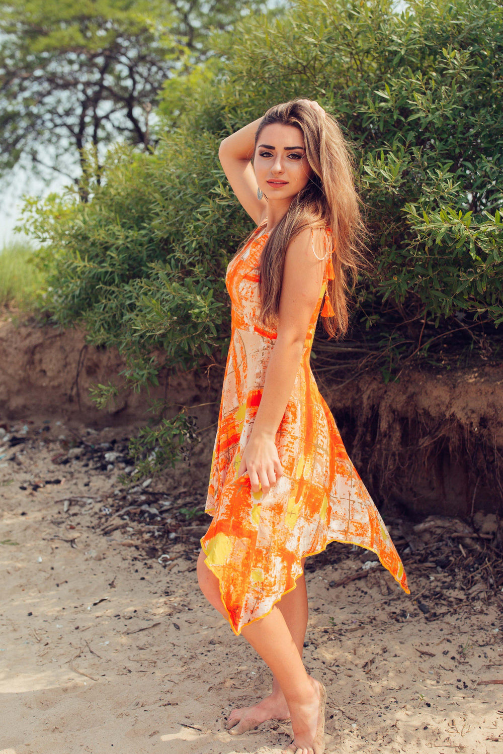 Tawny orange viscose rayon high-low dress with vibrant tie-dye patterns, V-neckline, and fluid silhouette.