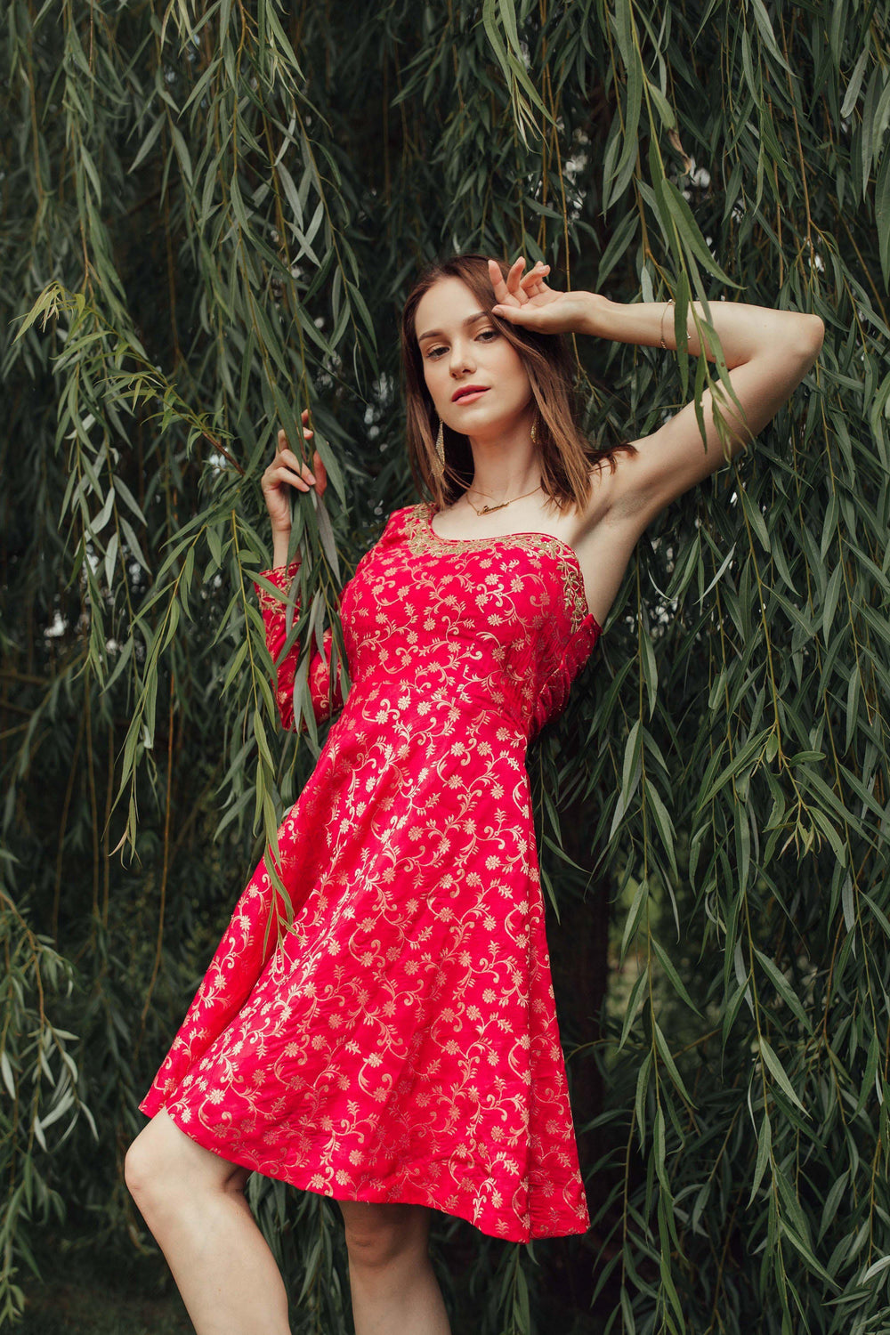 Dark pink silk one-shoulder mini dress with all-over golden hand embroidery, worn by a model.